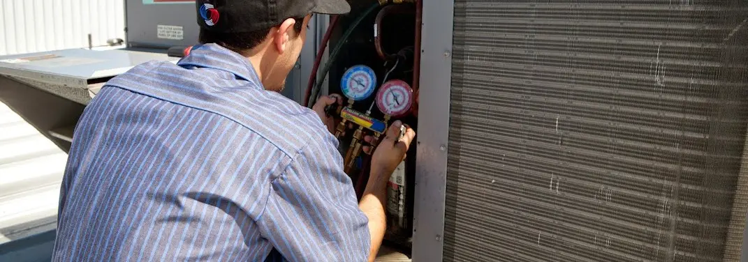 HVAC technician servicing a condenser unit in Carlsbad