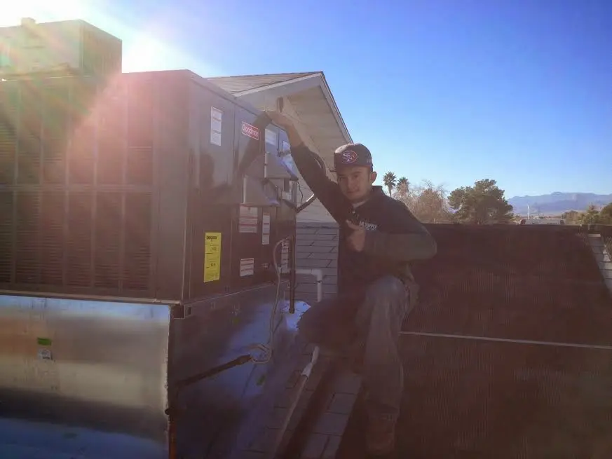 HVAC technician performing Air Duct Repair on a rooftop unit in Carlsbad